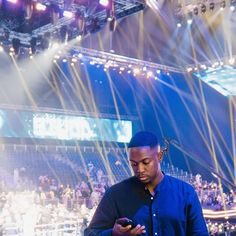 a man standing in front of a stage holding a cell phone and looking at it