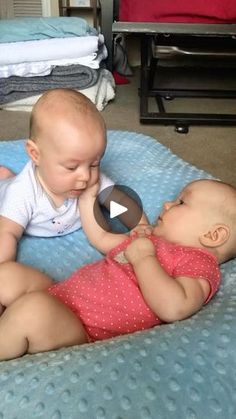 two babies playing with each other on a bed