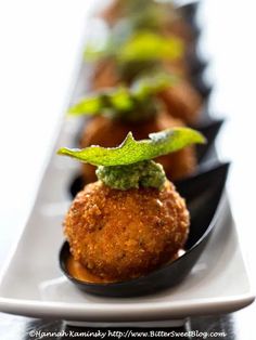 several appetizers are lined up on a long white plate with green garnishes