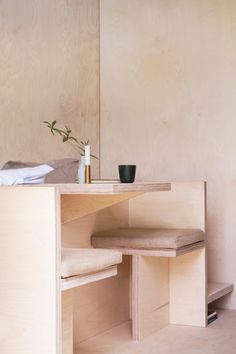 a wooden table with two stools and a vase on it in front of a mirror