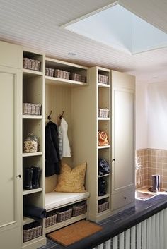 an organized mud room with white cabinets and baskets on the shelves, including a bench