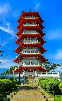 a tall red and white pagoda with steps leading up to it