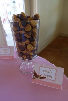 a glass vase filled with cookies on top of a pink table cloth covered tablecloth