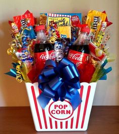 a popcorn box filled with soda, candy and candies is displayed on a table