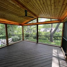 an empty covered porch in the middle of a wooded area with wood floors and metal railings