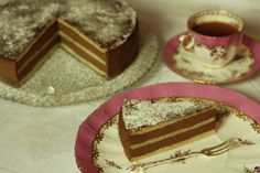 two plates with slices of cake on them next to a cup and saucer filled with tea