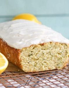 a loaf of lemon zucchini bread sitting on top of a cooling rack next to sliced lemons