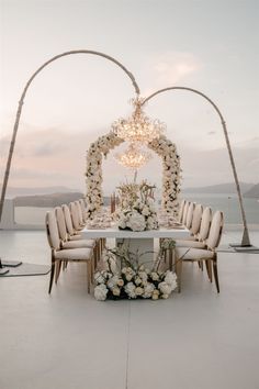 an outdoor wedding setup with white flowers and chandelier on the top of it