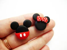 two mickey and minnie mouse earrings are shown in the palm of someone's hand