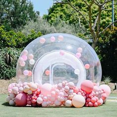 an inflatable bubble ball with pink and white balloons on the ground next to it