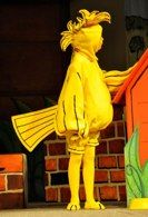 there is a statue of a yellow fish next to a red house and brick wall