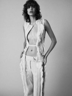 a black and white photo of a woman with curly hair wearing a feathered vest