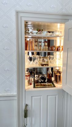 an open cabinet with many bottles and glasses in it