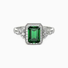 an emerald and diamond ring on a white background