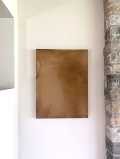 a painting is hanging on the wall next to a brick fireplace in a white room