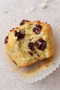 a half eaten chocolate chip muffin sitting on top of a paper cupcake liner