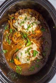 an overhead view of some food in a crock pot with sauce and parsley