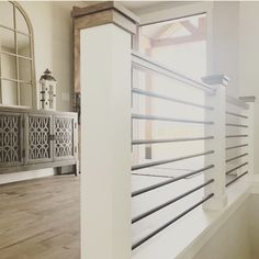 the inside of a house with wood floors and white railings in front of a window