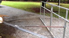 a wooden bench sitting next to a metal fence on top of a gravel road in front of a truck