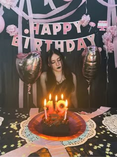 a woman sitting in front of a birthday cake with lit candles on top of it