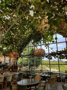 the inside of a restaurant with lots of tables and chairs under a tree filled ceiling