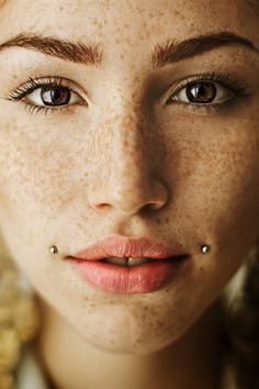 a woman with freckles and piercings on her nose