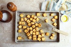 a pan filled with tofu next to a wooden spoon