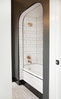 a white bath tub sitting inside of a bathroom next to a shower head and door