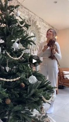 a woman standing next to a christmas tree