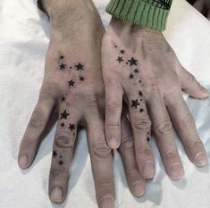 two hands with stars tattooed on them