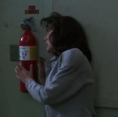 a woman holding a fire extinguisher in front of her face and looking at the wall