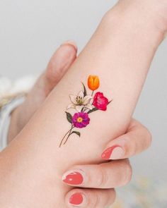 a woman's hand with a flower tattoo on her left wrist and the other arm