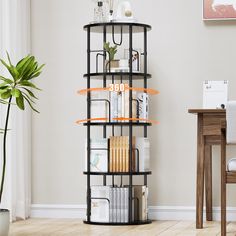 a black shelf with books and magazines on it in a room next to a table