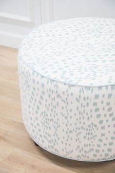 a white and blue ottoman sitting on top of a hard wood floor