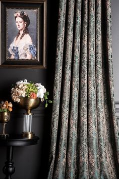 a painting is hanging on the wall next to a table with flowers in front of it