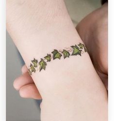 a woman's wrist tattoo with ivys on it