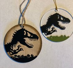 two wooden ornaments with dinosaurs on them