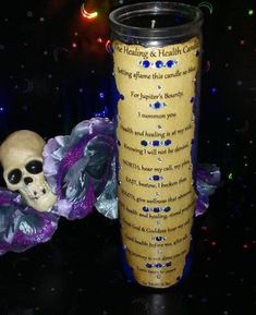 a candle with a skull on it next to a purple flower and skeleton figurine