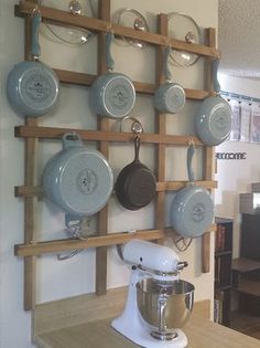 pots and pans are hanging on the wall in a kitchen with wooden shelves above