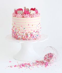 a cake with pink frosting and sprinkles sitting on top of a white plate