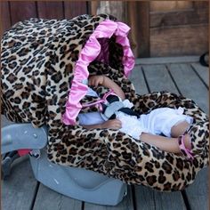 a baby in a leopard print car seat cover