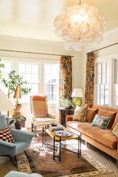 a living room filled with furniture and a chandelier hanging over the top of it