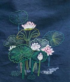 an embroidered piece of cloth with water lilies and leaves in the center on a dark blue background