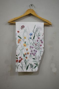 a towel hanging on a wooden hanger next to a wall with flowers painted on it