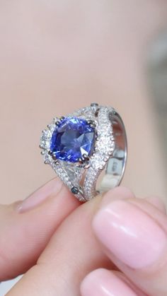 a close up of a person holding a ring with a blue stone in the middle