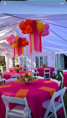 an outdoor tent with tables and chairs covered in pink, orange and yellow tablecloths