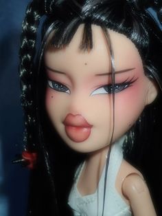 a close up of a doll's face with long black hair and blue eyes