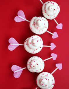 cupcakes with white frosting and pink sprinkles are arranged on a red background