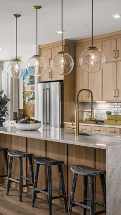 a large kitchen with marble counter tops and wooden cabinets, along with stools that match the hardwood flooring