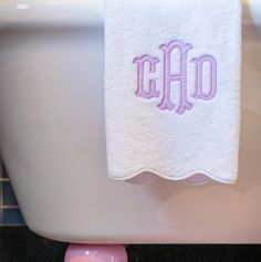 a towel hanging on the edge of a bathtub with an embroidered monogrammed word